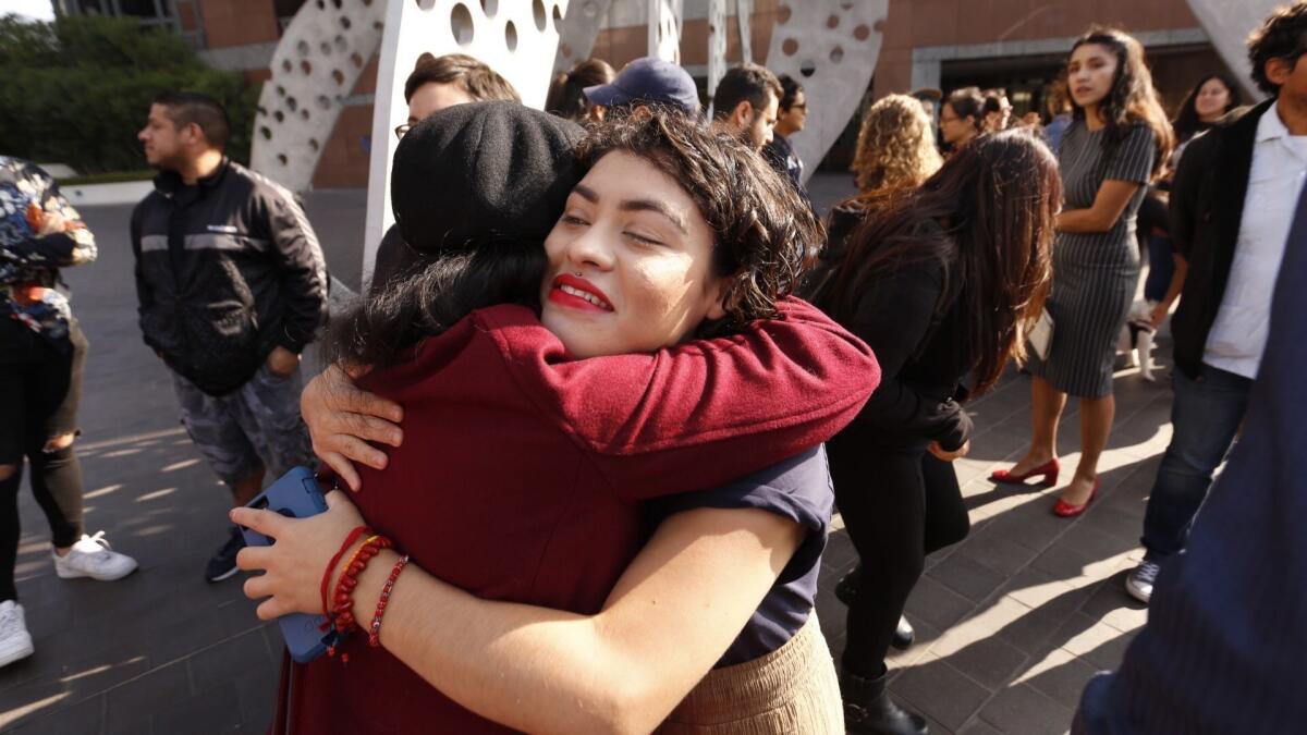 Claudia Rueda hugs fellow Cal State student Alicia Moseley, after a news conference in front of the Roybal Federal Building in Los Angeles.