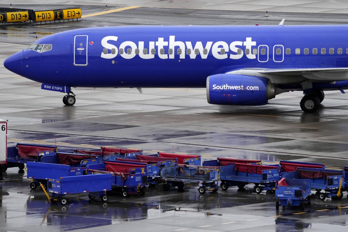 A Southwest Airlines jetliner passes empty luggage carts at an airport.