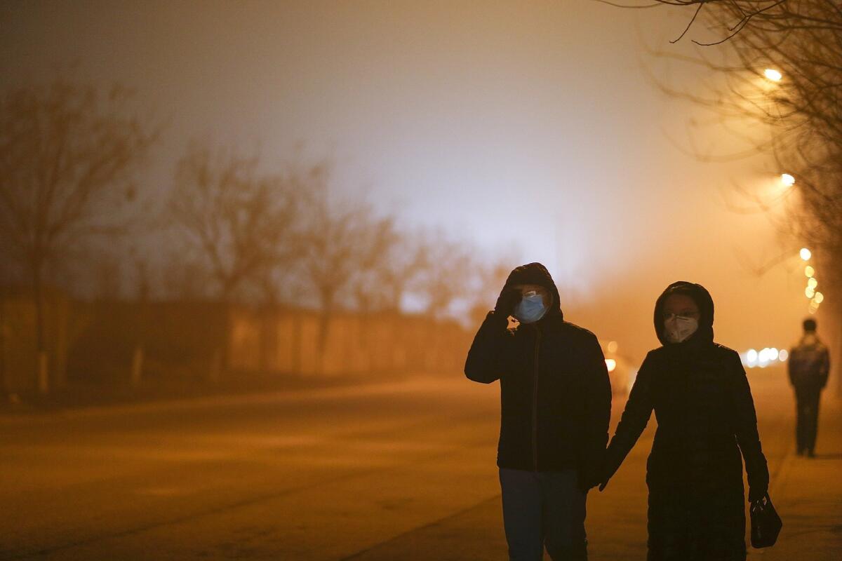 People walk through Beijing wearing masks on Dec. 22, a heavy pollution evening.