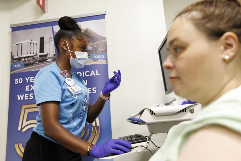 Los Angeles, CA - September 06: Sherri Pender (right) waits to receive her Covid-19 vaccination from Breiona Lang LVN at the Kaiser Permanente Venice Clinic on Friday, Sept. 6, 2024 in Los Angeles, CA. (Carlin Stiehl / For the Times)