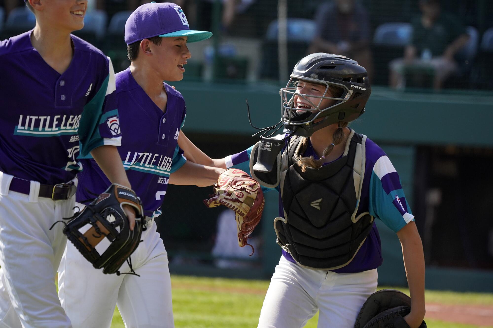 Abilene, Texas catcher Ella Bruning, right, celebrates with pitcher Dylan Regata, center, after the side is retired.