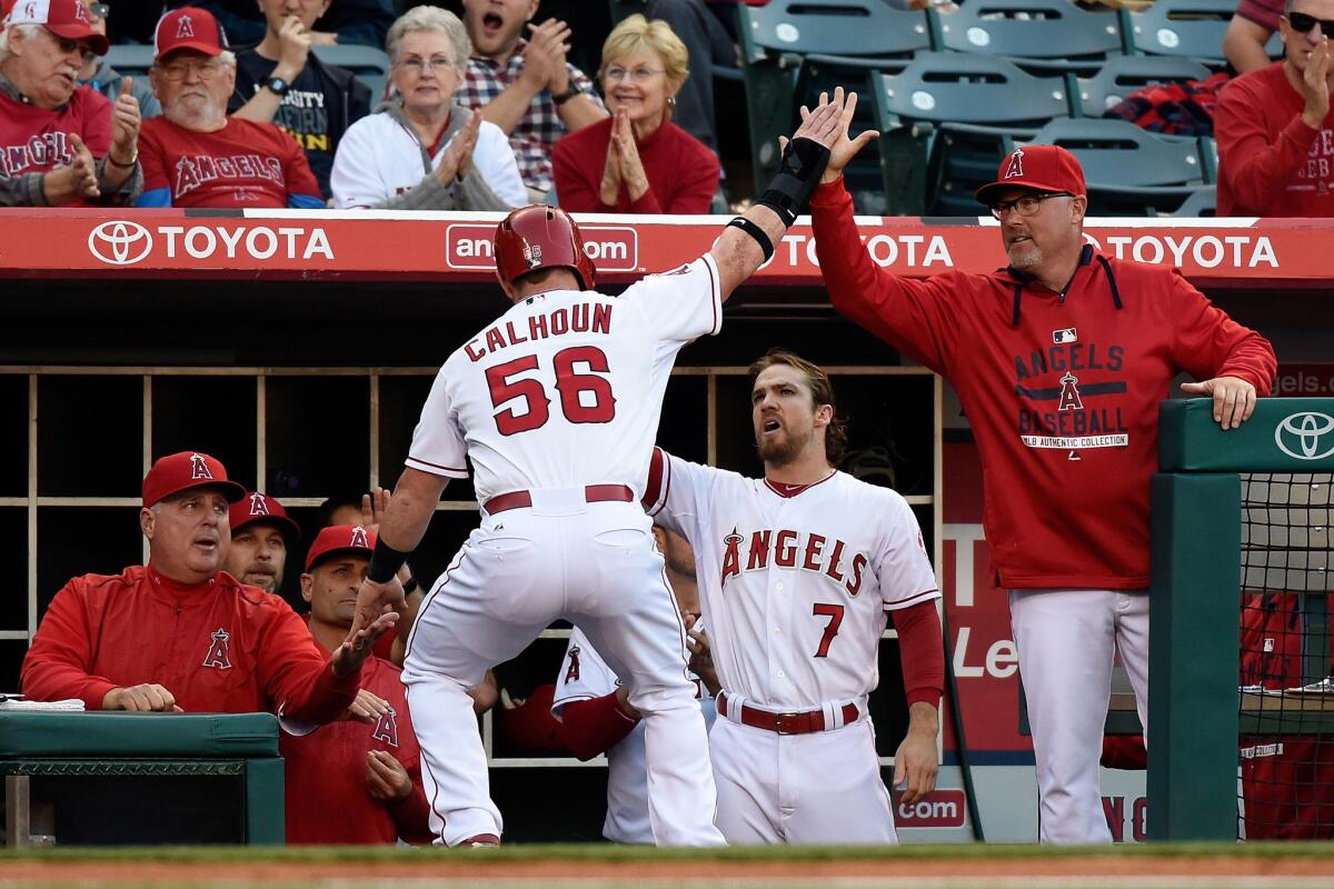 Kole Calhoun returns to the Angels dugout after scoring in the first inning of a 6-5 loss to Houston on Saturday night.