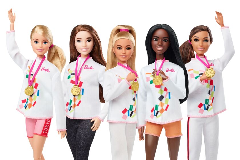 Five Barbie dolls wearing athletic apparel and gold medals