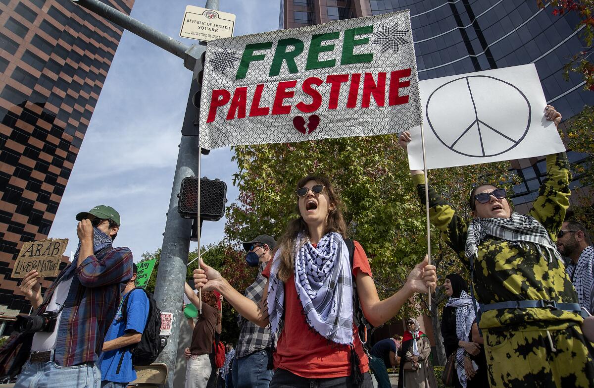 Marchers hold signs, one reading "Free Palestine" and another with a peace symbol.