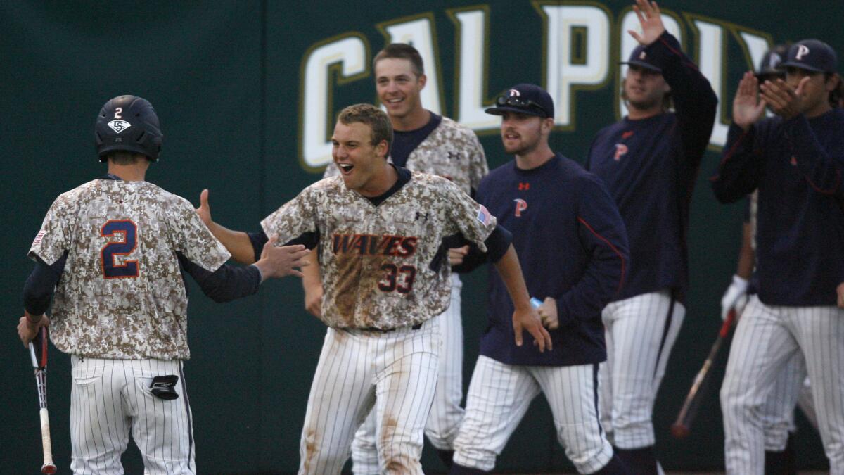 Pepperdine's Hutton Moyer, left, celebrates with his teammates after scoring the go-ahead run in the seventh inning of the Waves' 2-1 win over Cal Poly on Saturday.