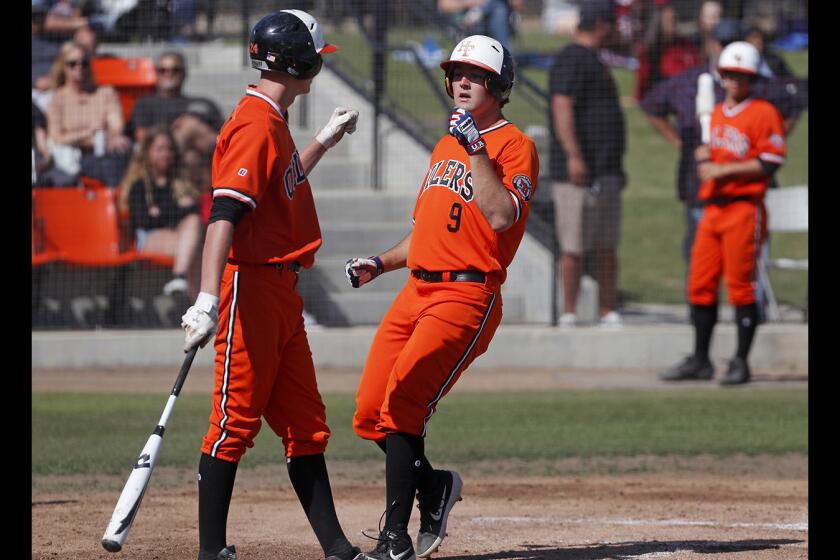 Josh Hahn (9) celebrates a run with Huntington Beach High teammate Cole DiMarco during the first inning of a Surf League home game against Edison on Tuesday.