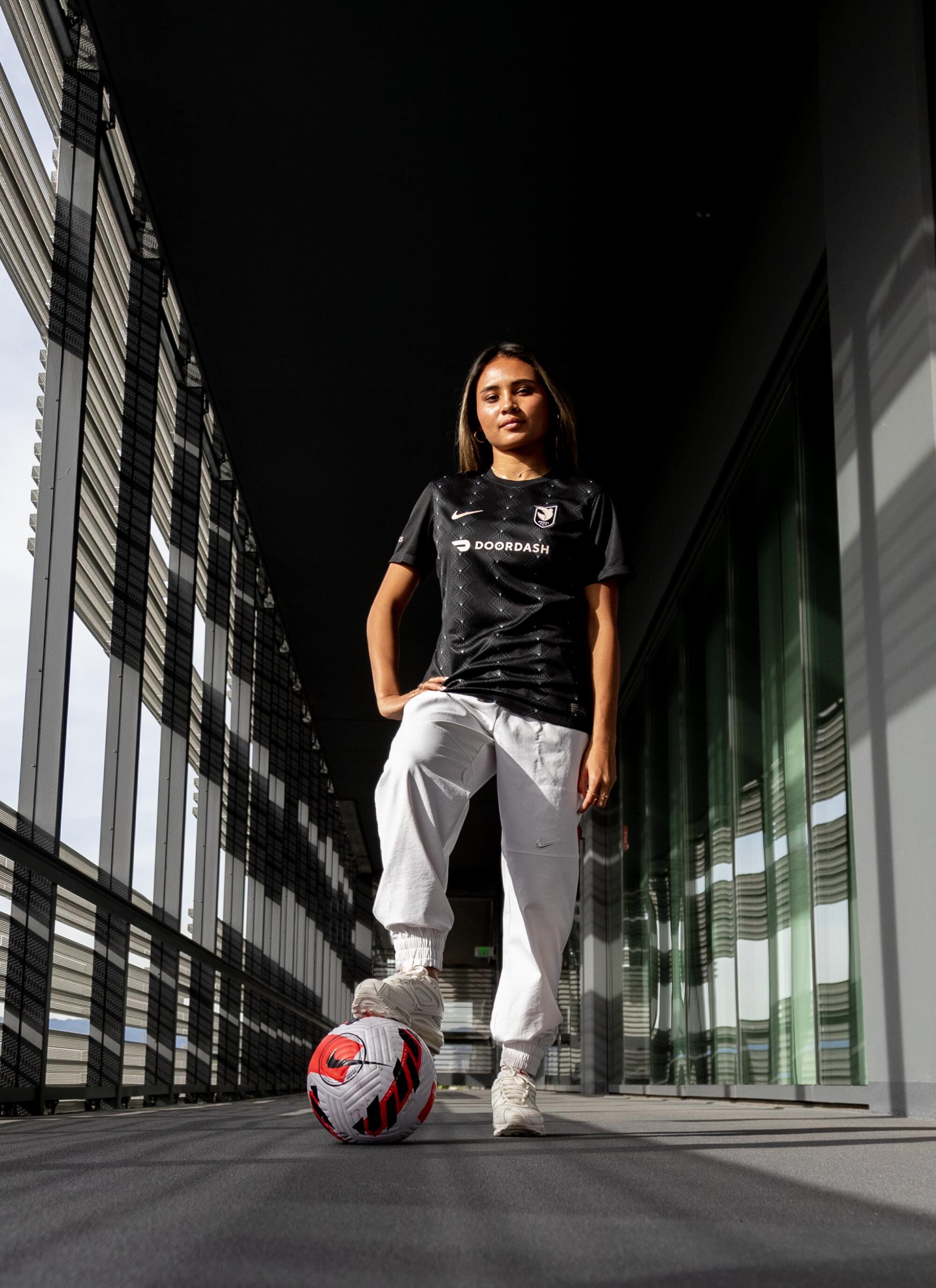 Alyssa Thompson stands in a hallway with her foot on a soccer ball.