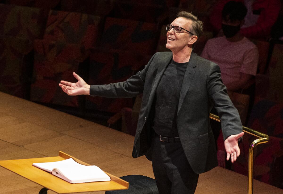 Grant Gershon conducts onstage in a black suit