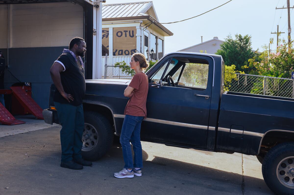 A man, left, and a woman face each other next to a pickup truck