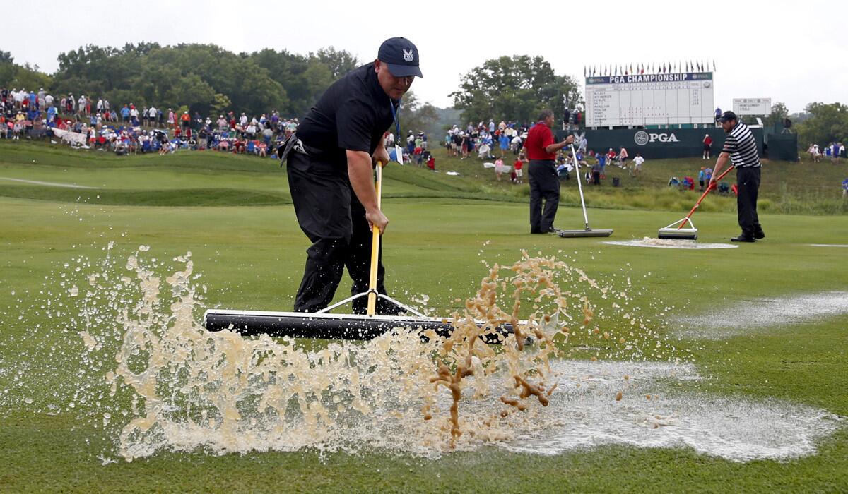 Course workers push rain water off the first hole at Valhalla Golf Club during a weather delay in final round of the PGA Championship on Sunday.