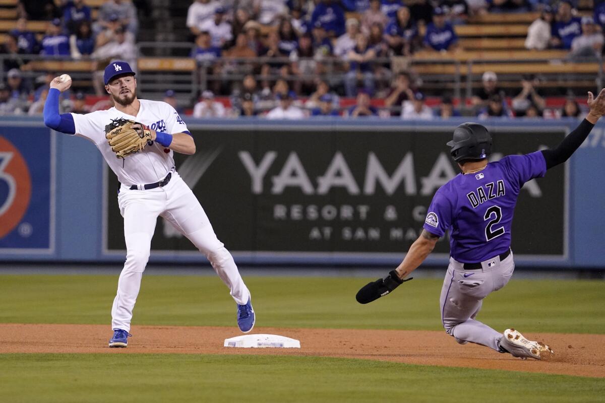 The Rockies' Yonathan Daza is forced out at second by Dodgers second baseman Gavin Lux as Lux throws to first.