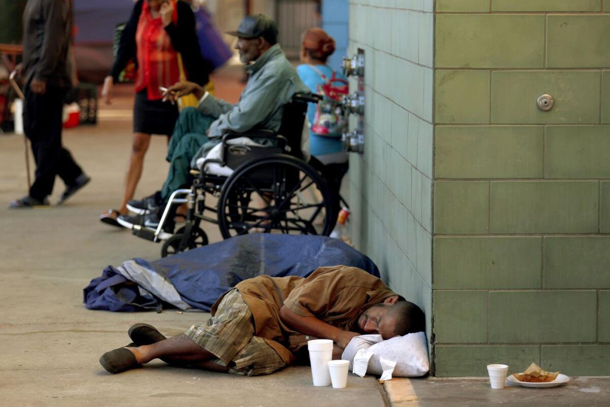 A man sleeps on the sidewalk in front of the Union Rescue Mission in the skid row neighborhood of Los Angeles.