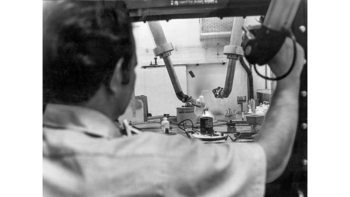 An operator at the Santa Susana facility of Atomics International works with radioactive materials from a safe distance.
