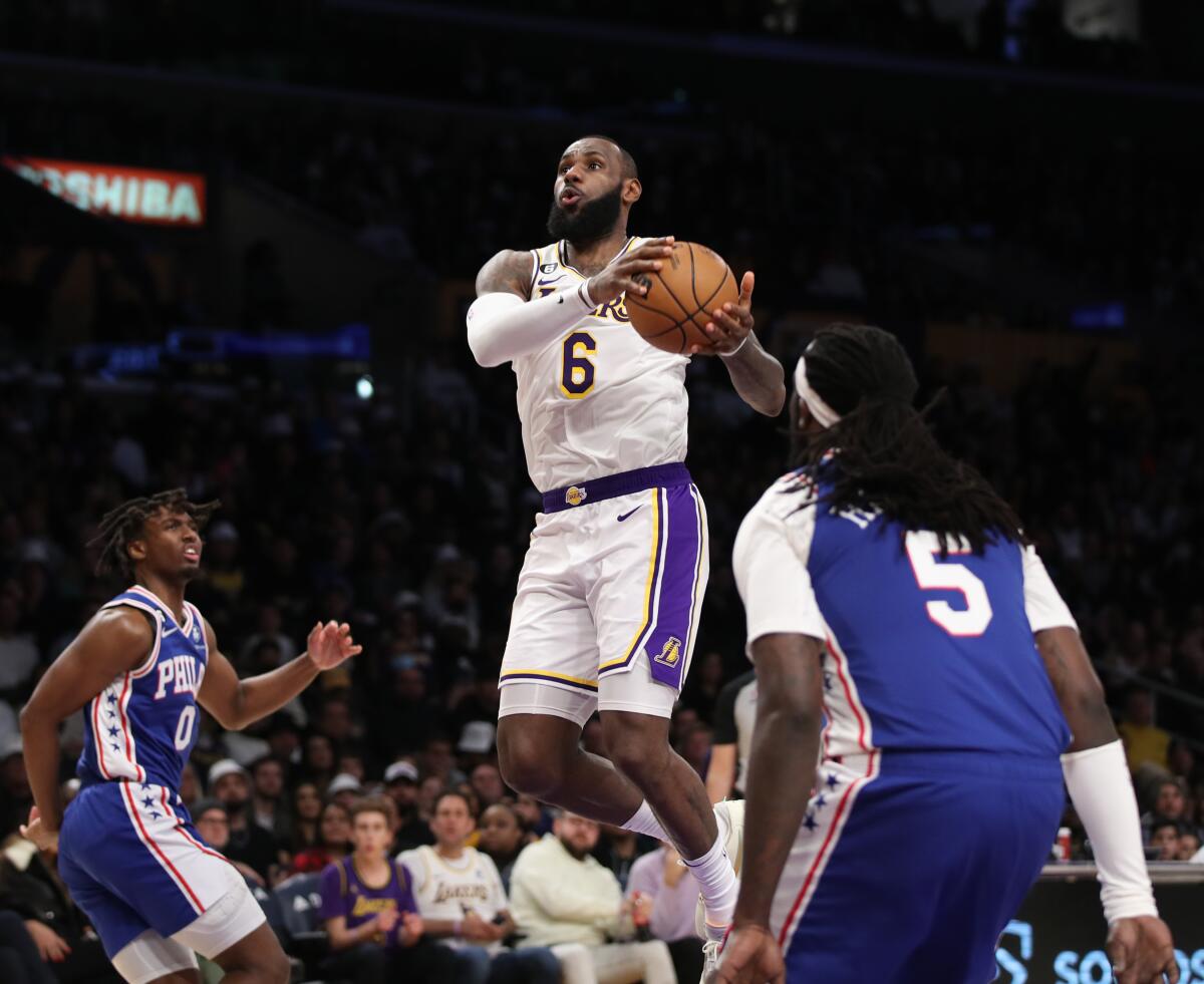 Lakers star LeBron James drives to the basket past 76ers point guard Tyrese Maxey and center Montrezl Harrell.