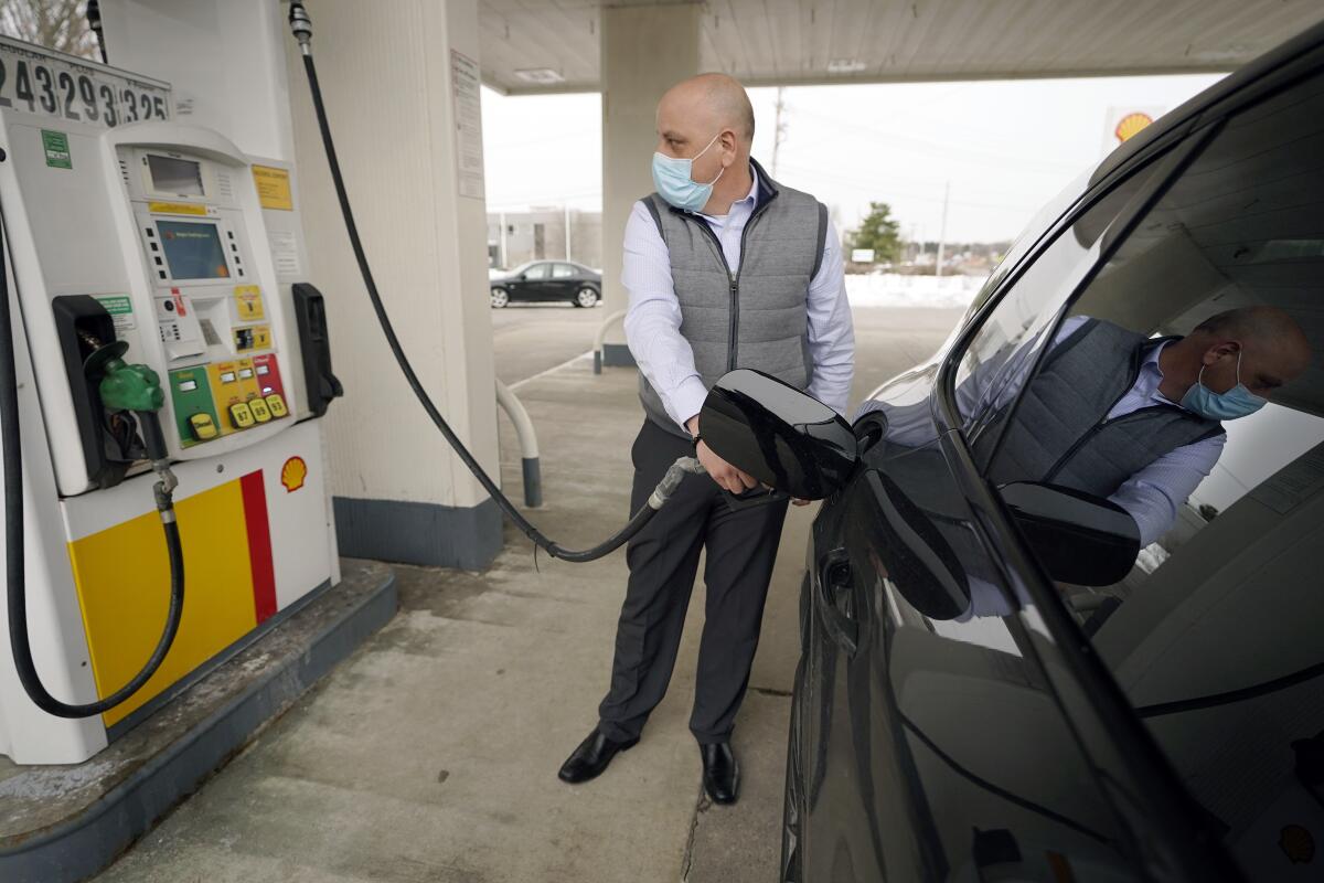 Jeremy Heskett of Boston pumps gasoline at a Shell gas station in Westwood, Mass. 