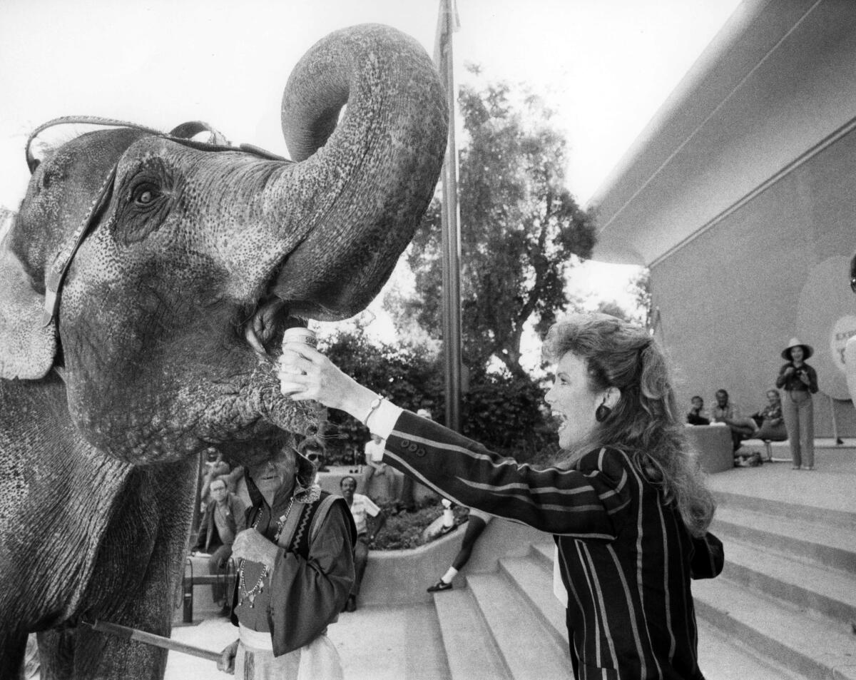 A woman pretends to give an elephant a drink in an episode of "General Hospital."