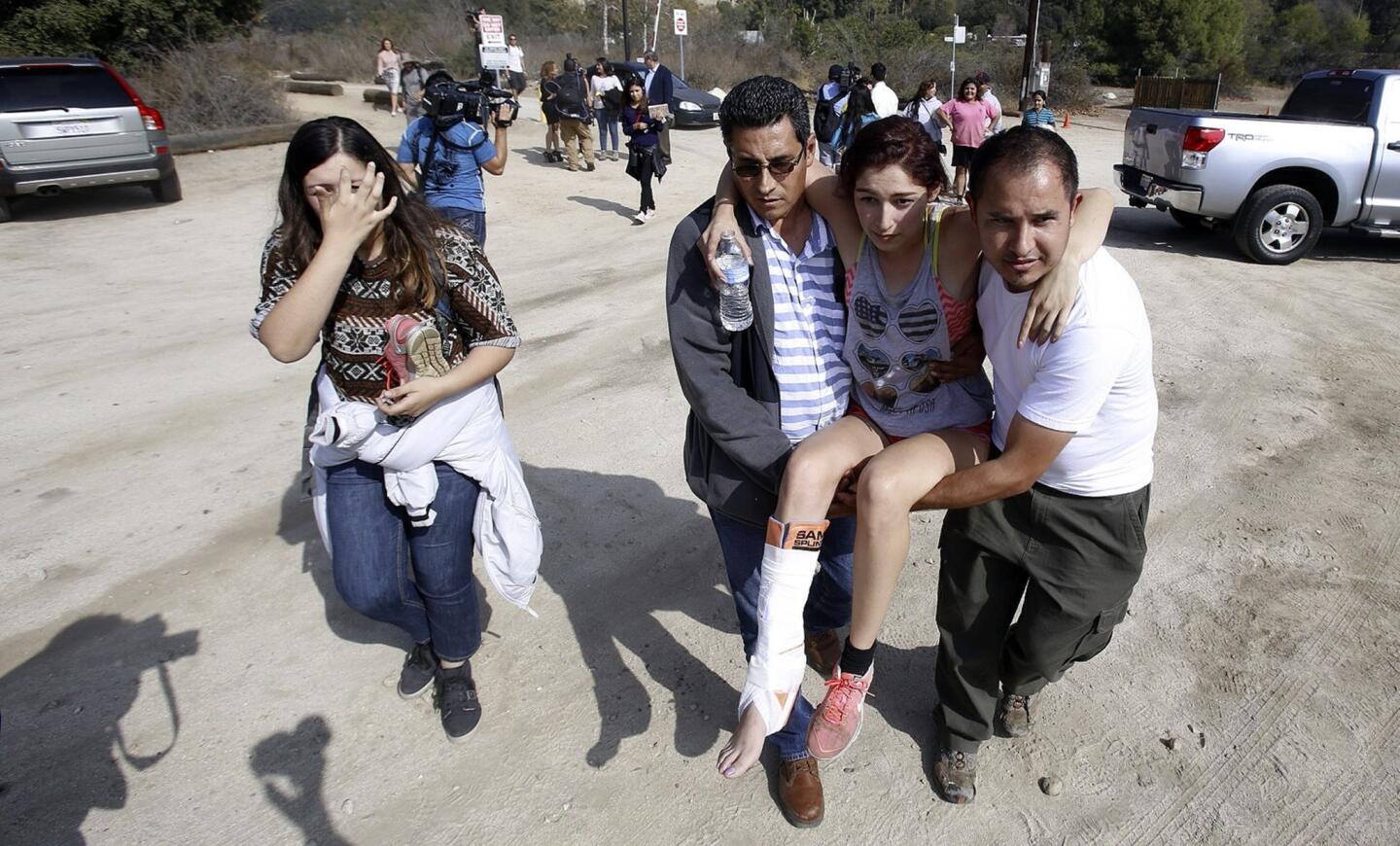 Claudia Ortiz, 20, is carried by her stepfather, Raphael Palacios, left, and friend Christian Armenta, right, after being rescued near Eaton Canyon in Altadena. Ortiz suffered an ankle injury during the operation.