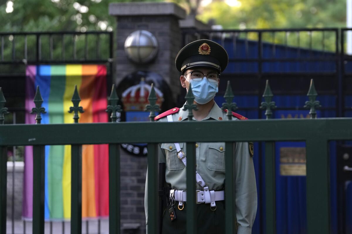 Chinese police officer with rainbow flag in background