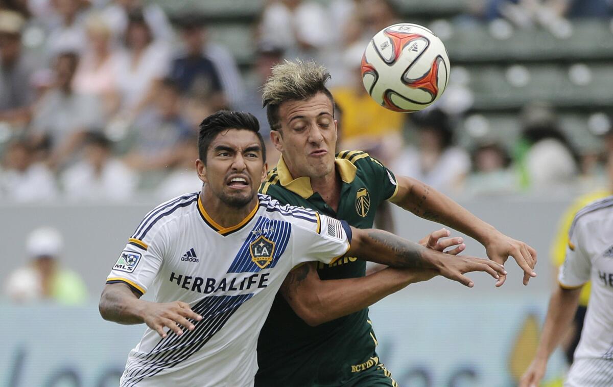 The Galaxy's A.J. DeLaGarza and Portland's Maximiliano Urruti fight for the ball during a match on Aug. 2.