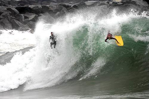 A surfer, left, and bodyboarder are removed from their boards while surfing big waves, some as high as 20 feet, at the Wedge in Newport Beach, today. Most Southern California south-facing beaches saw waves up to 12 feet, but at the Wedge, wave heights tend to double in size because of refracting wave energy off the Newport Harbor jetty.