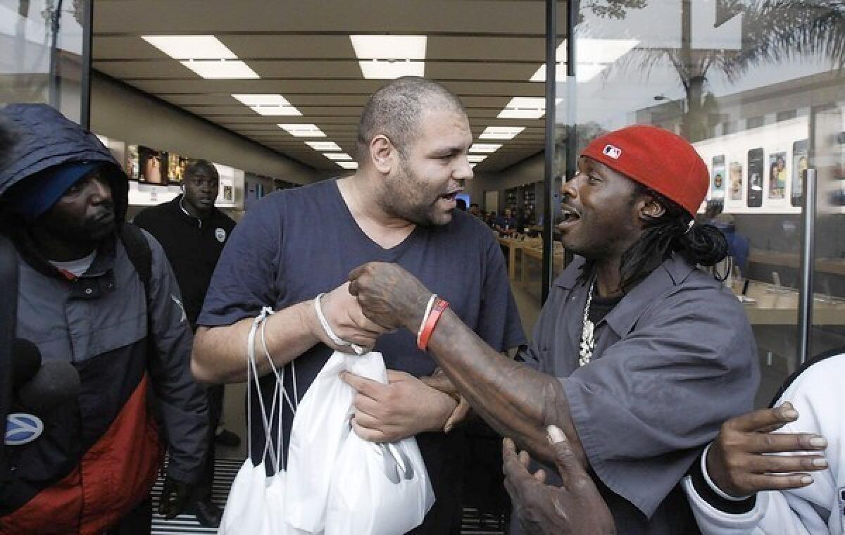 A man, at right, confronts a businessman who had hired him to hold a place in line outside the Apple store in Pasadena. At least two people were arrested after fistfights erupted.
