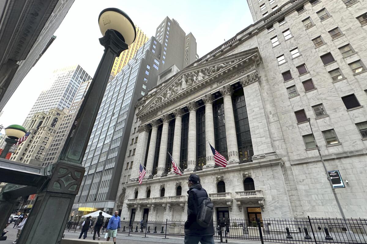 People pass the New York Stock Exchange on Wednesday, March 13, 2024, in New York. Global shares are mixed in muted trading as optimism set off by a record rally on Wall Street gradually ran out of momentum. (AP Photo/Peter Morgan)