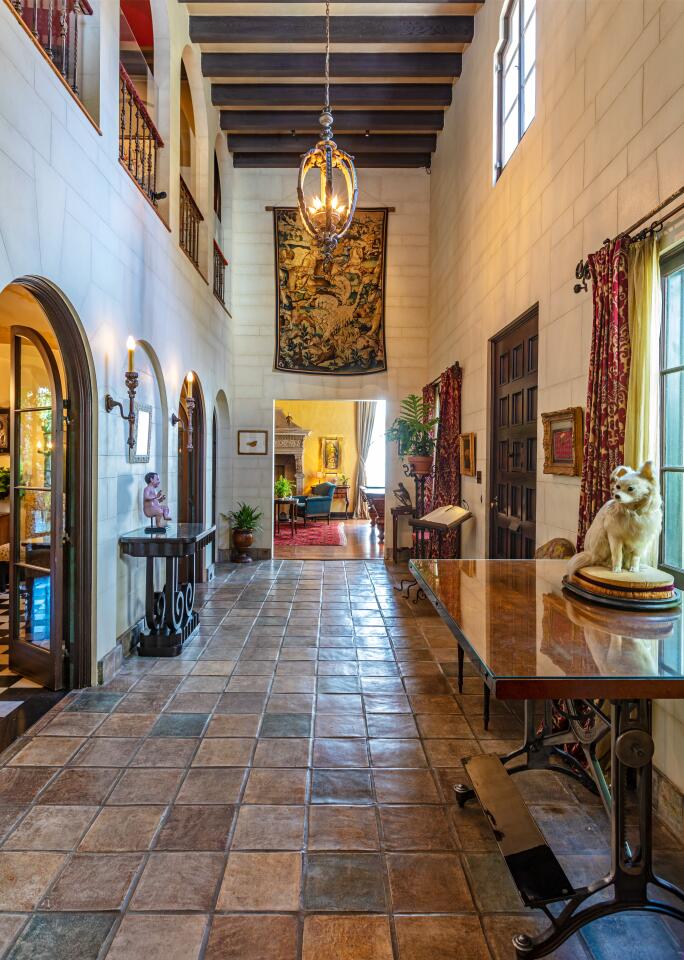 The entry with a stone tile floor, rounded doorways, side tables and windows.
