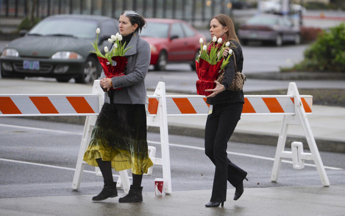 Leslie King, left, and Tenille Beseda carry flowers to place at the entrance of the Clackamas Town Center Mall in Clackamas, Ore., where a shooting killed two victims and left a third seriously injured.