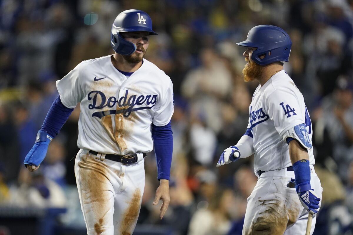 Gavin Lux, left, celebrates with Justin Turner after scoring off of a triple hit by Trea Turner during the third inning.