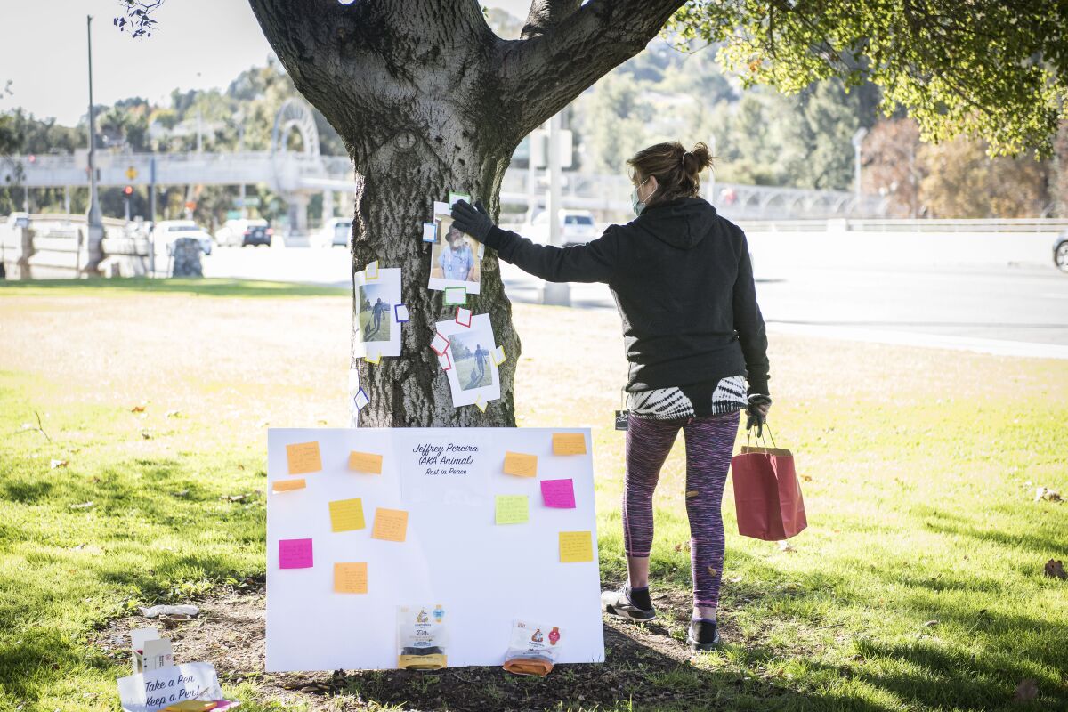 Cynthia Caldwell, a neighbor of Jeffrey Pereira in the homeless encampment, touches his photo at a vigil in Bond Park.