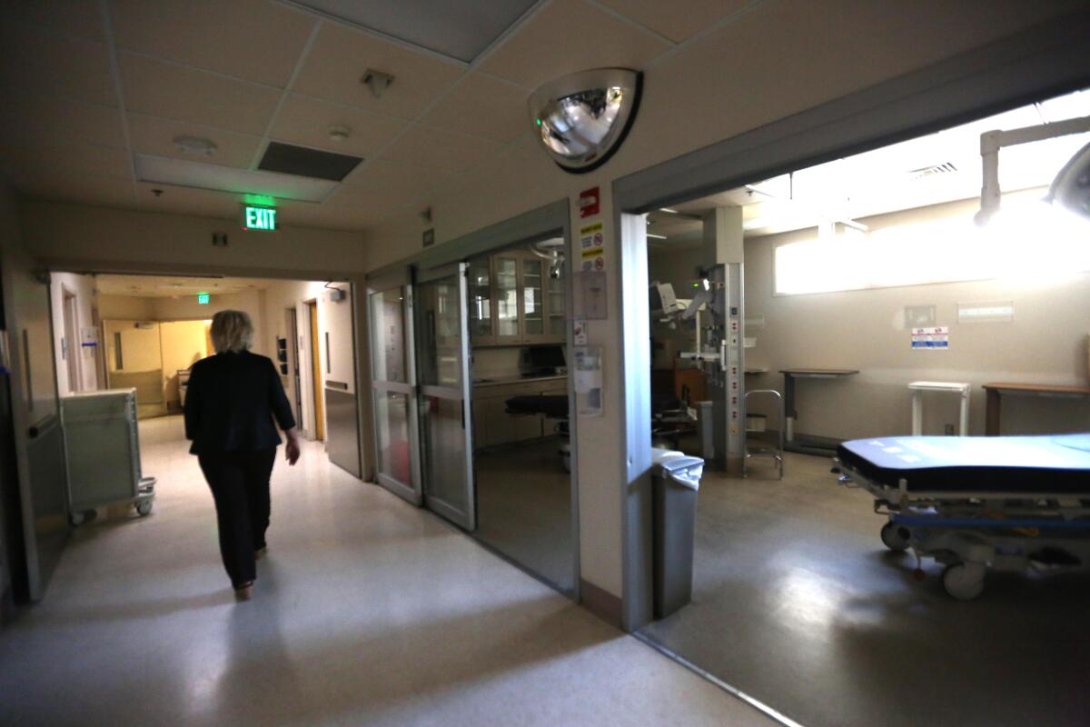 A woman walks down the hall of an empty hospital.