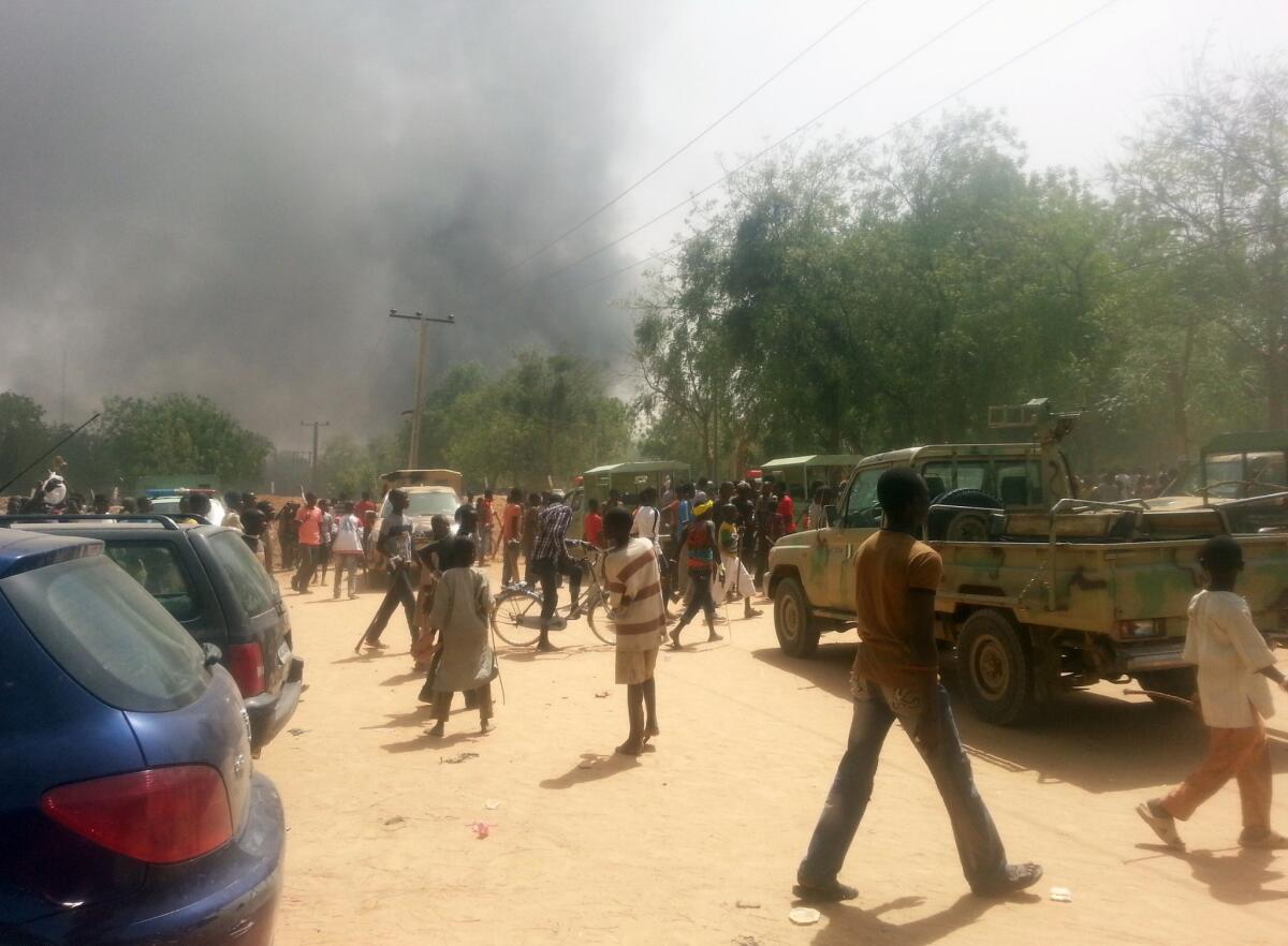 People look at smoke rising after suspected Boko Haram Islamists attacked a military base in the northeast Nigerian city of Maiduguri.