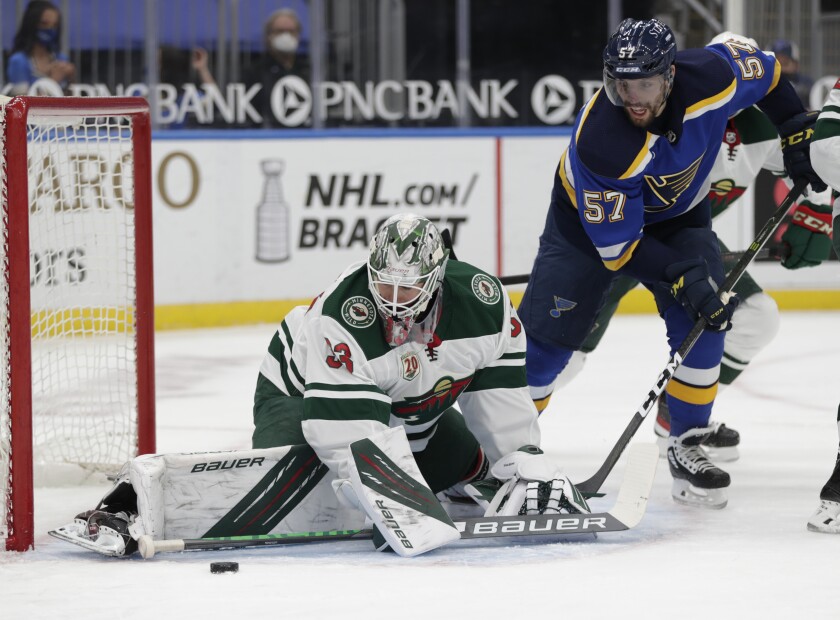 Minnesota Wild goaltender Cam Talbot (33) makes a stick save as St. Louis Blues' David Perron (57) looks for the loose puck in the second period of an NHL hockey game, Wednesday, May 12, 2021 in St. Louis. (AP Photo/Tom Gannam)