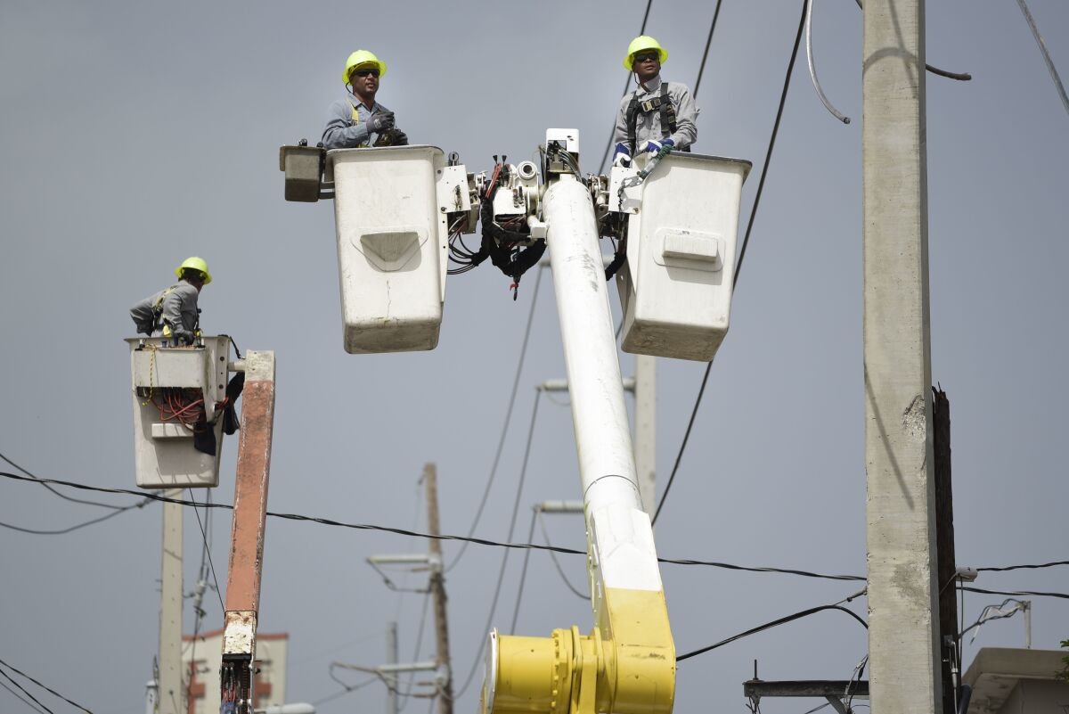 FILE - Puerto Rico Electric Power Authority workers repair distribution lines damaged by Hurricane Maria in the Cantera community of San Juan, Puerto Rico, Oct. 19, 2017. Efforts to restructure some $9 billion in debt held by Puerto Rico’s power company hit a new snag Thursday, Dec. 1, 2022, following multiple failed attempts to end its bankruptcy. (AP Photo/Carlos Giusti, File)