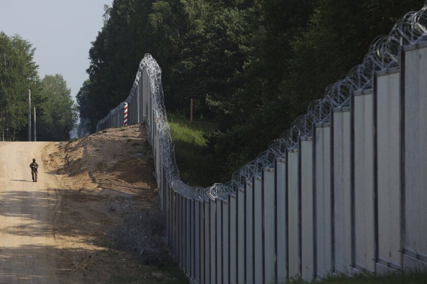 A Polish border guard patrols the area of a newly built metal wall on the border between Poland and Belarus, near Kuznice, Poland, Thursday, June 30, 2022. A year after migrants started crossing into the European Union from Belarus to Poland, Polish Prime Minister Mateusz Morawiecki and top security officials visited the border area on Thursday to mark the completion of a new steel wall. (AP Photo/Michal Dyjuk)