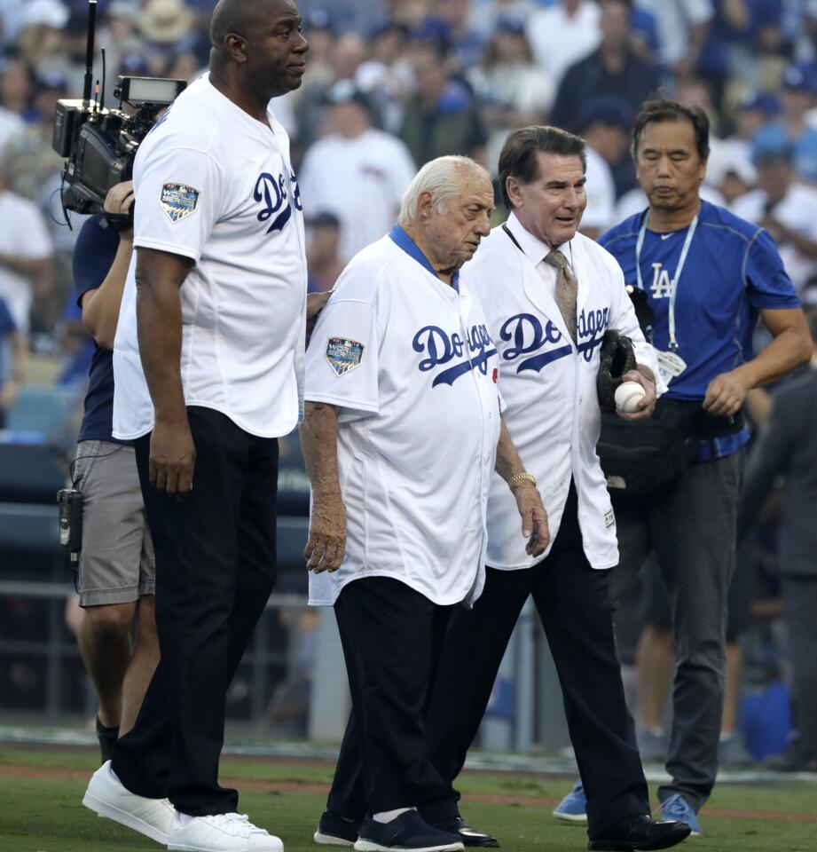 Former Lakers player Magic Johnson and former Dodgers players Tommy Lasorda and Steve Garvey walk off after posing for a photo prior to Game 3 of the World Series.