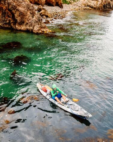 A kayaker near rocky islands.