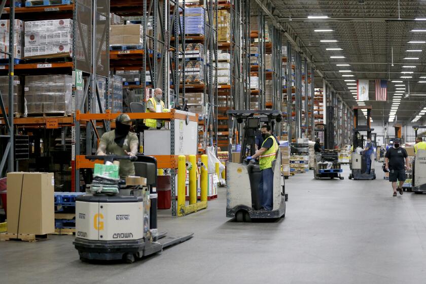 RIVERSIDE, CA -- APRIL 28: Associates fill orders for both Ralphs and Food 4 Less grocery stores at the Ralphs Distribution Center on Tuesday, April 28, 2020, in Riverside, CA. The 80 acre, 1.2 million square feet, full service distribution center employing 1100 workers took on more product after automated warehouses couldn't keep up with the spike in demand after restaurants were shuttered. (Gary Coronado / Los Angeles Times)