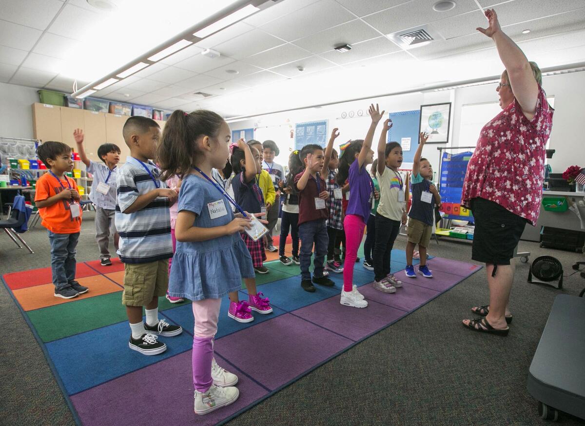 La maestra de kindergarten de la escuela primaria John Gibbins U-T Zamorano, Jennifer Smart, dirige a sus alumnos al cantar "This Land is Your Land" el lunes, el primer día de clases.