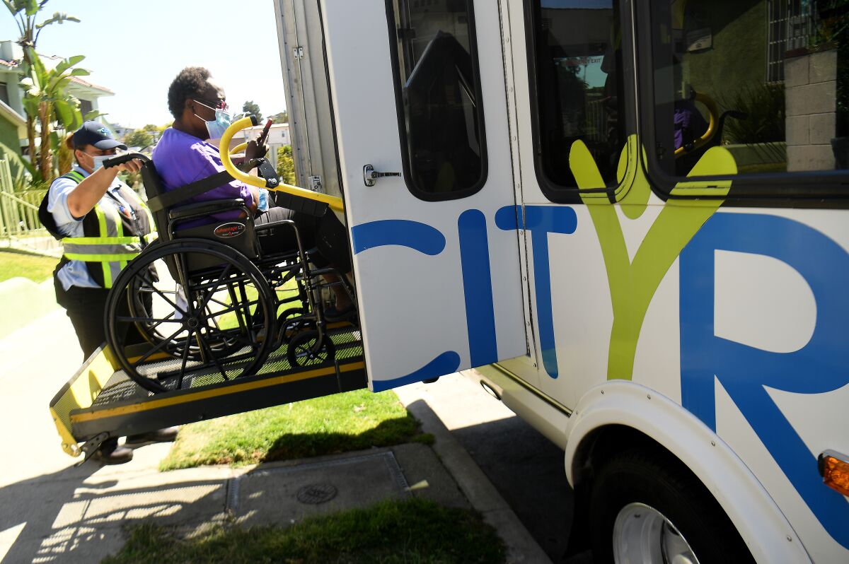 A homeless woman is loaded into a bus headed for a hotel in Echo Park Tuesday.
