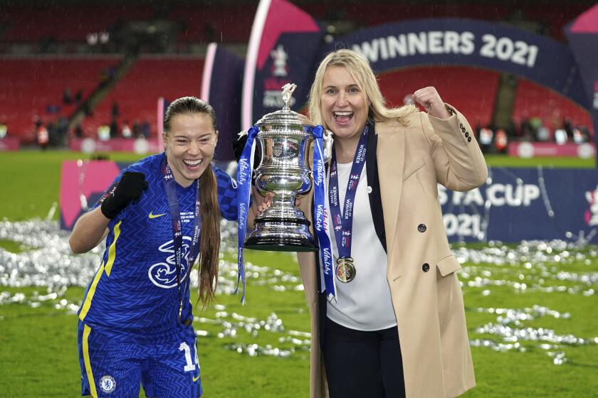 Chelsea's Fran Kirby, left and manager Emma Hayes celebrate with the trophy, after the women's FA Cup soccer final match between Arsenal and Chelsea, at Wembley Stadium, in London, Sunday, Dec. 5, 2021. (John Walton/PA via AP)