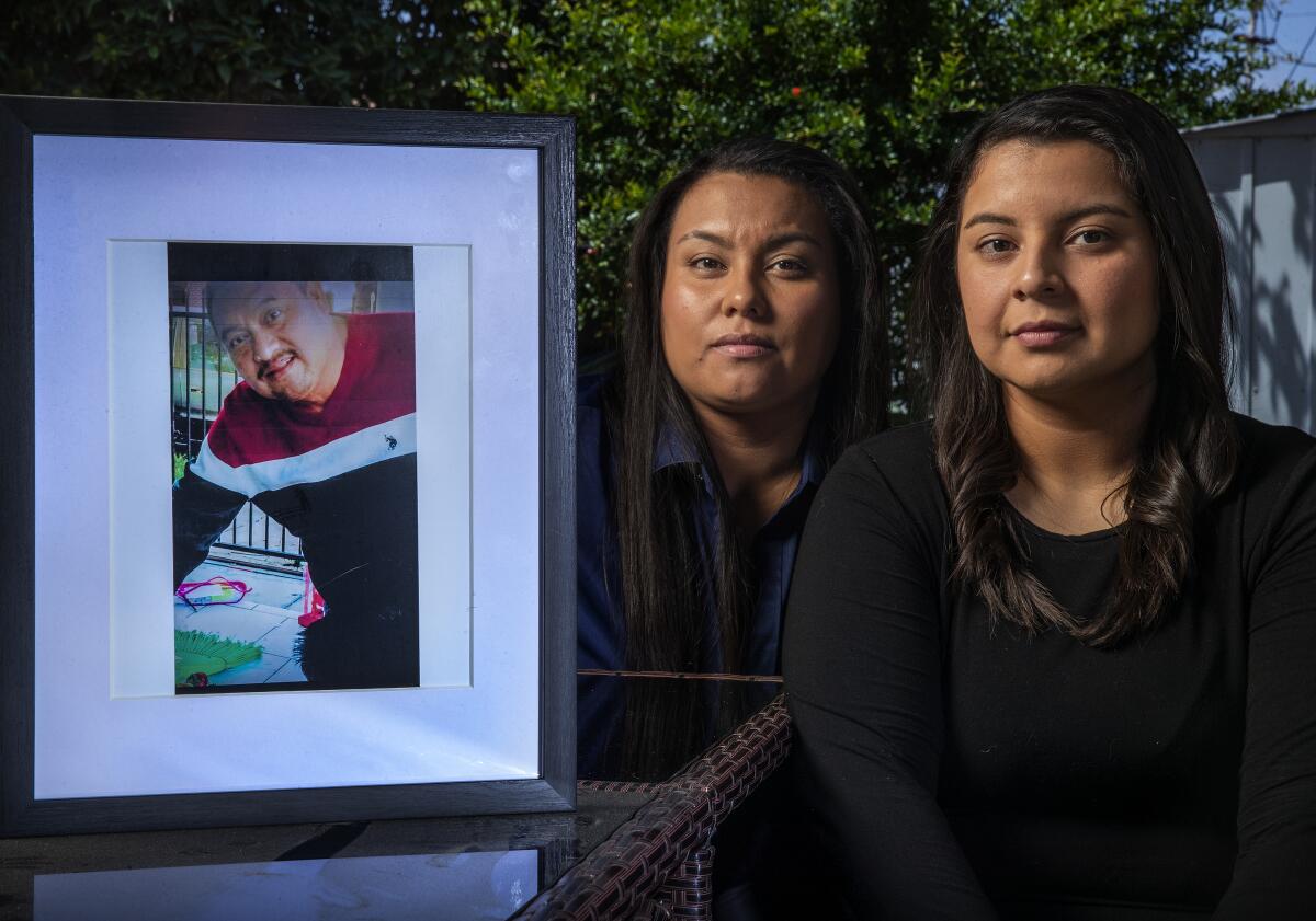 Johanna Garcia, left, and her sister Katherine, with a portrait of their late father, Enrique Garcia.