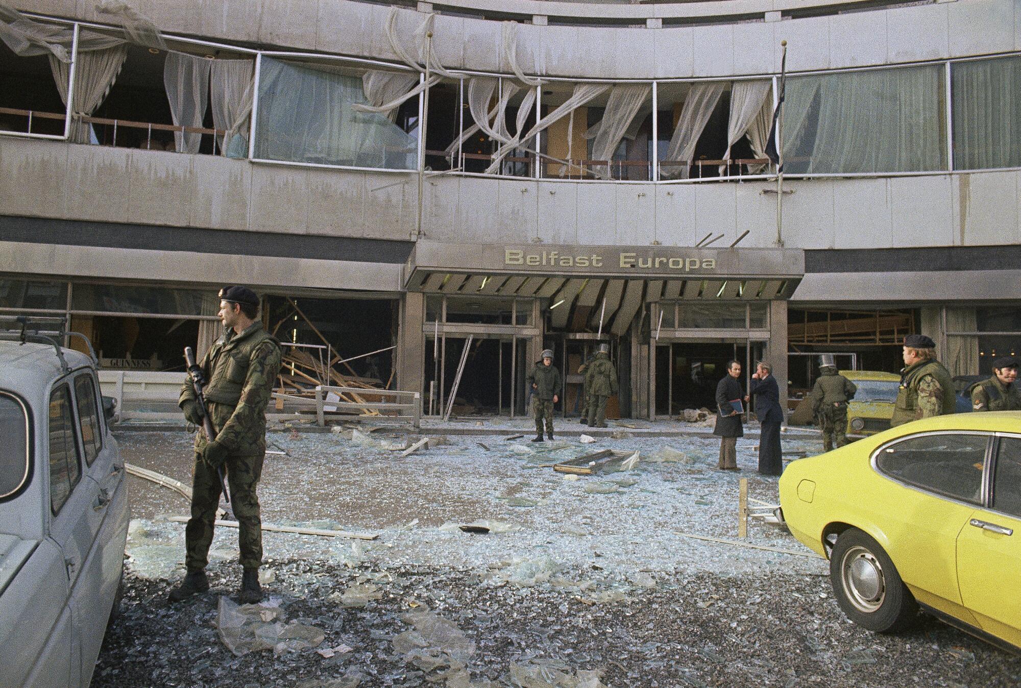 British troops stand guard as bomb experts search through the wreckage at a hotel.