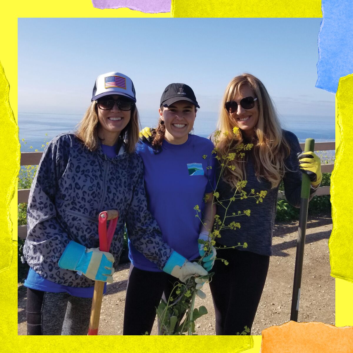 Three women stand holding shovels and a long plant with yellow flowers.