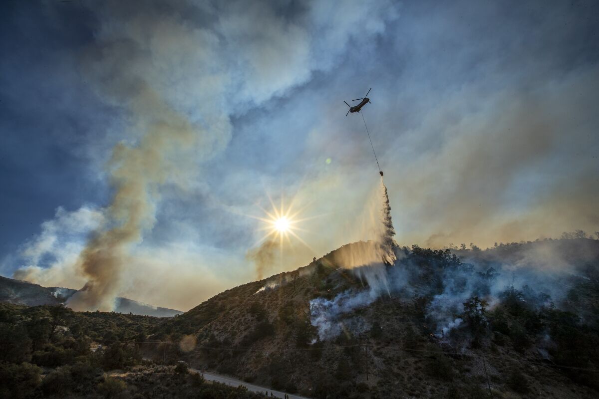 A water-dropping helicopter makes a run at the Bobcat fire in the Angeles National Forest near Llano.