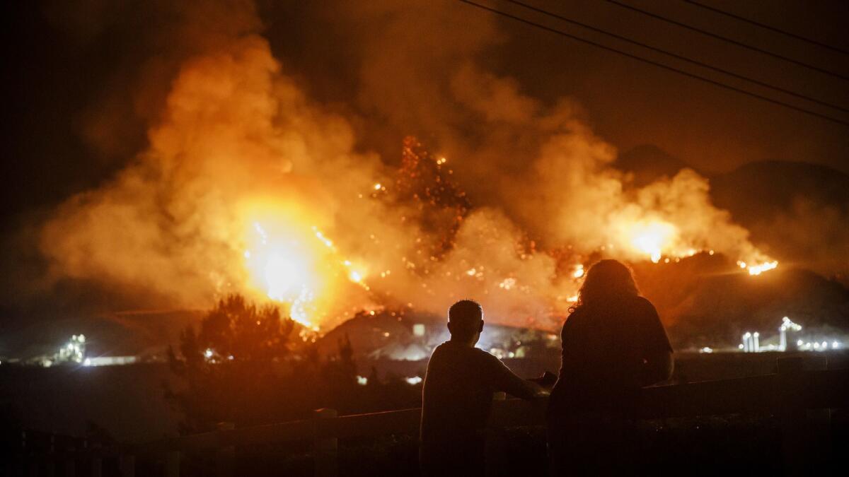 People watch flames as the Holy fire rages on a mountainside in Temescal Valley on Aug. 10.
