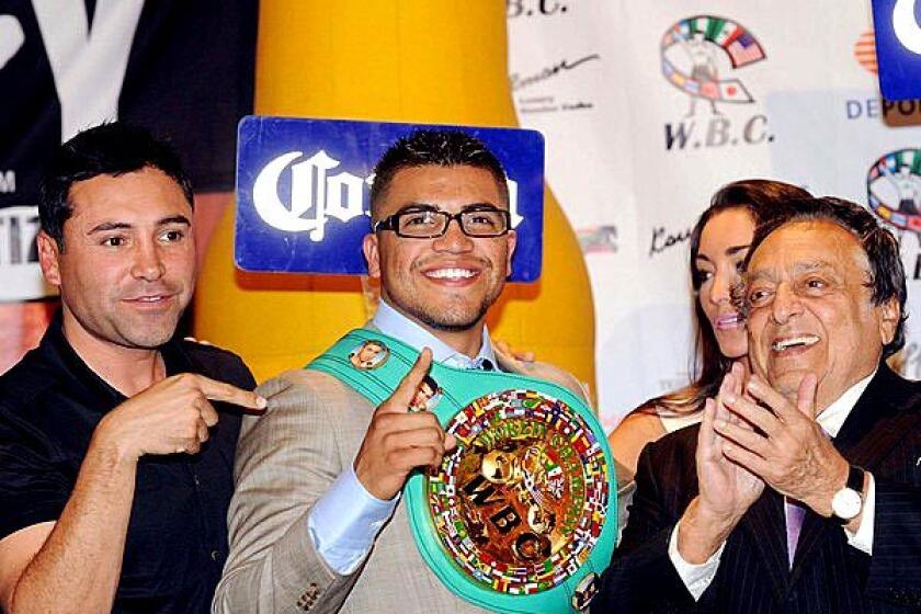 Oscar De La Hoya poses with Golden Boy Promotions boxer Victor Ortiz and WBC President Jose Suleiman during a news conference in Mexico City after Ortiz defeated Andre Berto for the WBC welterweight title.
