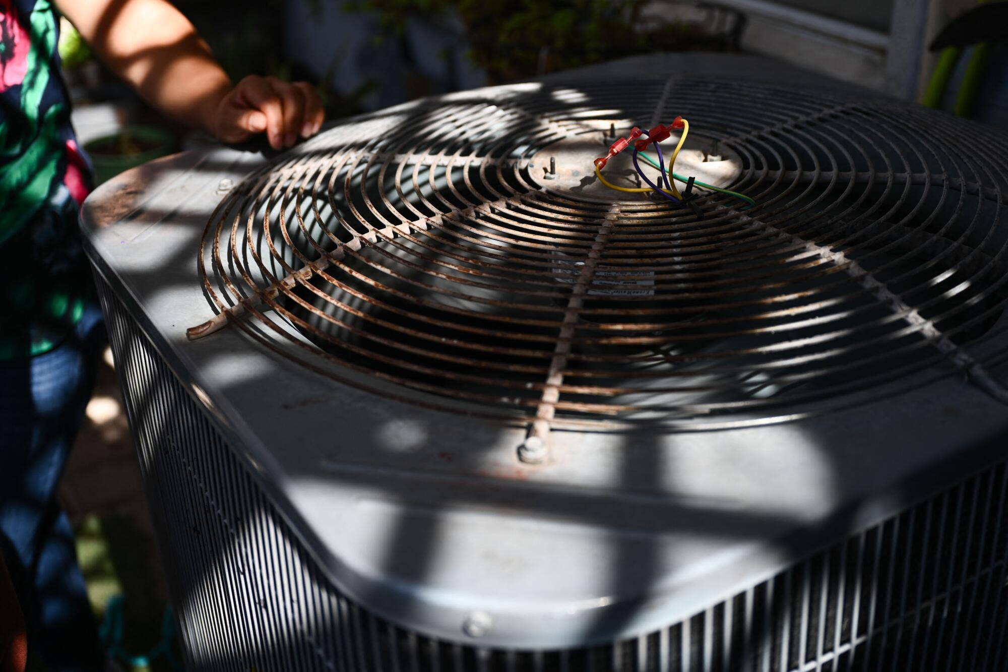 A photo of a person standing next to a machine with a fan under a circular metal grid 