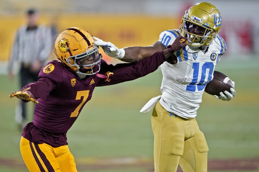 UCLA running back Demetric Felton shoves Arizona State tight end Ethan Long.