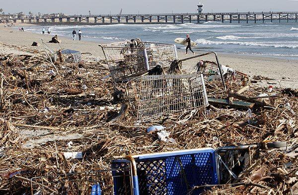 Trash and shopping carts litter the beach near Seal Beach Pier. Last week's storms brought debris down the San Gabriel River. "It's gross," one surfer said. "There's plastic bags everywhere."